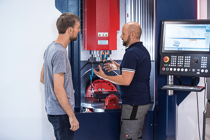 EMCO Service Trainer schult Mitarbeiter vor EMCO CNC Dreh- und Fräsmaschine